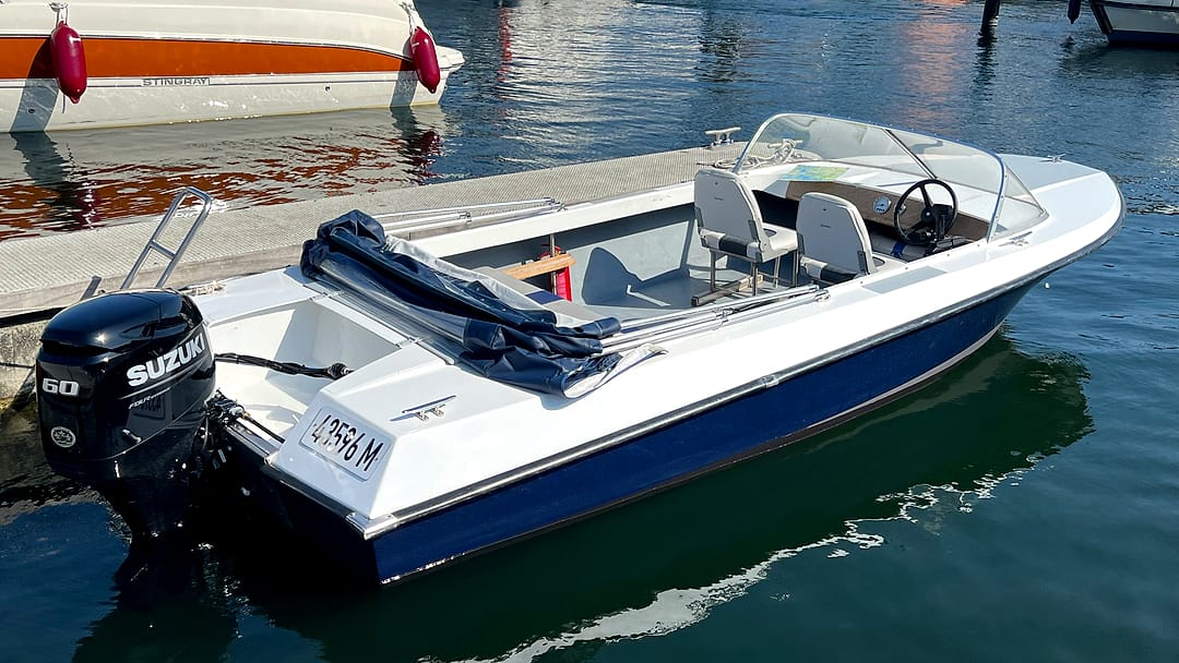 Sportliches Motorboot „Albatros“ mit Windschutzscheibe und Suzuki-Außenborder am Steg.